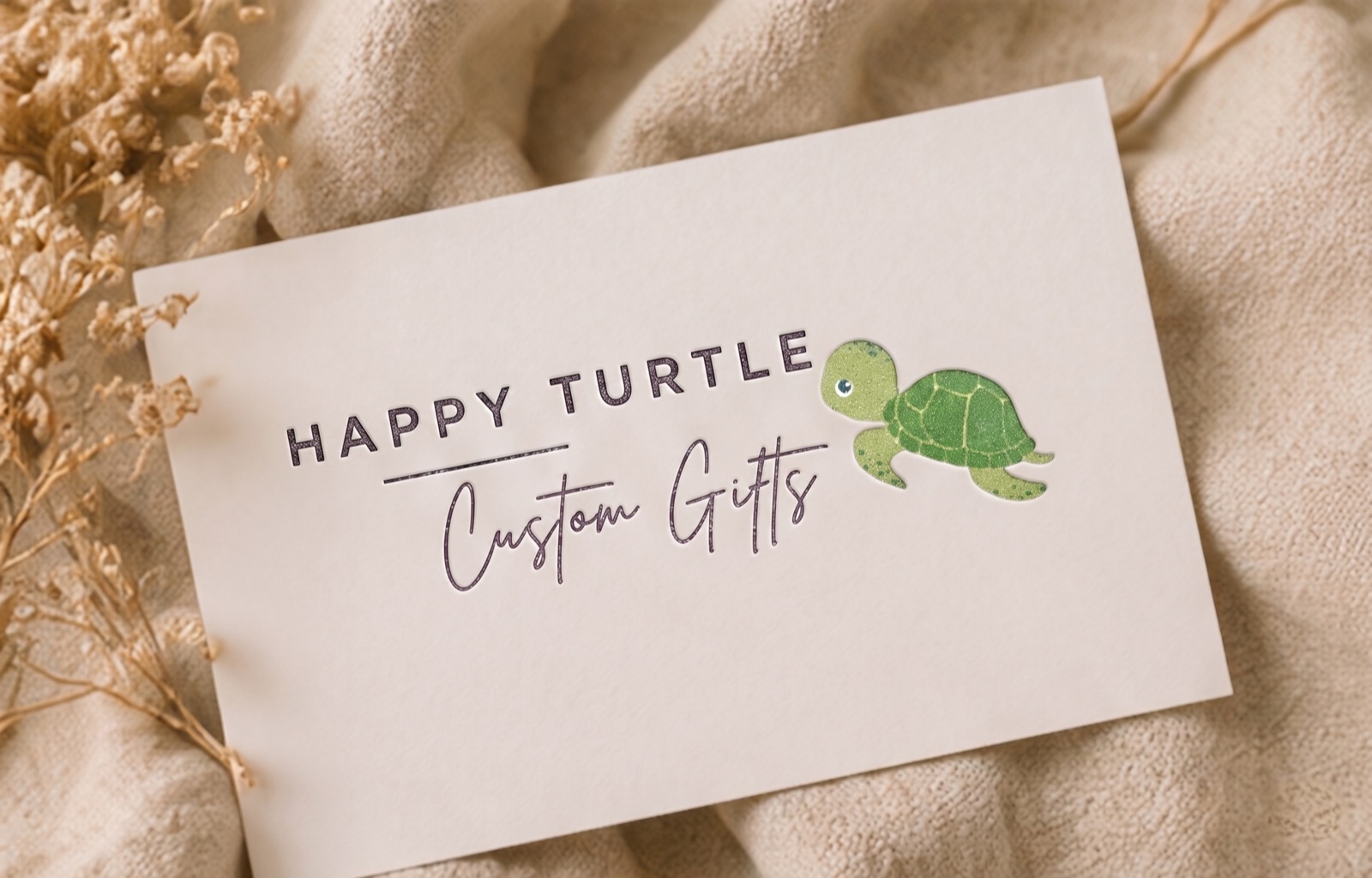 A Happy Turtle Custom Gifts card, laid on a knitted blanket beside dried flowers