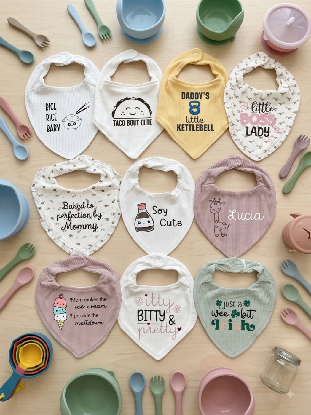 Twelve printed bandana bibs arranged with pastel bowls and spoons