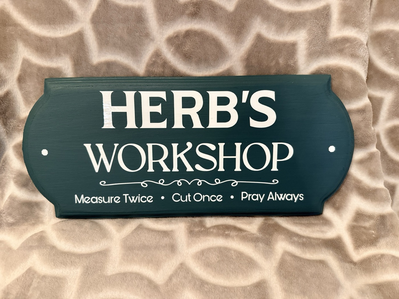 A painted wooden workshop sign reading Measure Twice, Cut Once, Pray Always